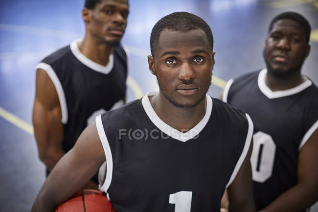 Retrato sério, focado jovem jogador de basquete masculino equipe vestindo camisas pretas — Fotografia de Stock