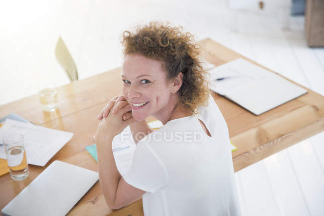 Retrato del joven trabajador de oficina sonriente en el escritorio - foto de stock