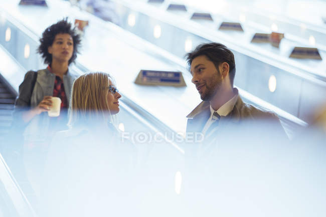 Gente de negocios hablando en escaleras mecánicas - foto de stock
