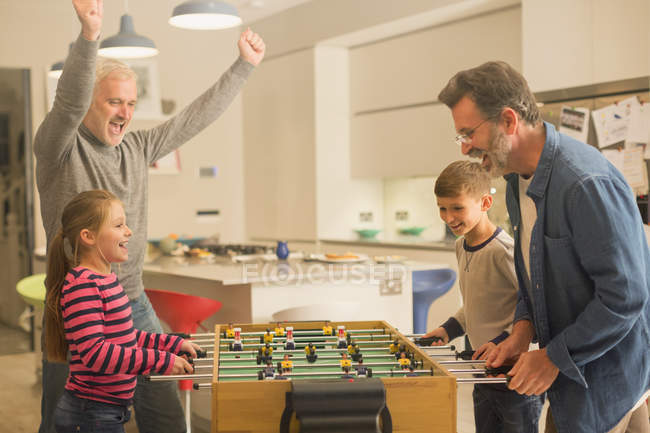 Male gay parents and children playing foosball — Stock Photo