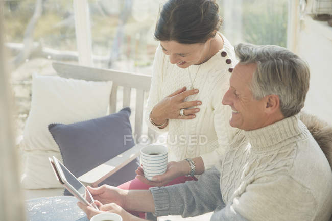 Ältere Paare trinken Kaffee und verwenden digitale Tablette auf der Veranda — Stockfoto