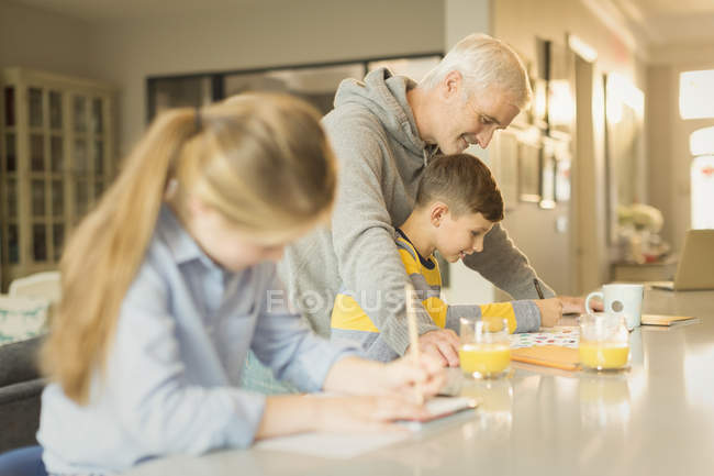 Father helping son with homework at counter — Stock Photo