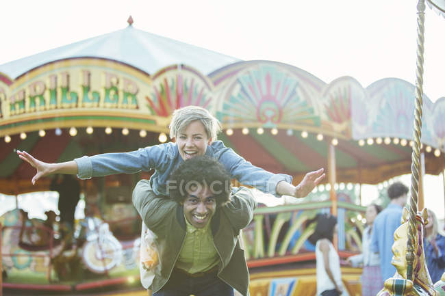 Retrato de jovem casal multirracial se divertindo no parque de diversões — Fotografia de Stock