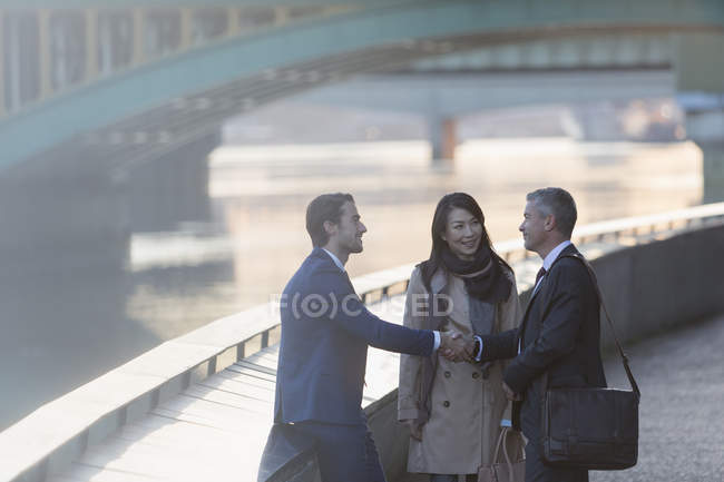 Uomini d'affari che stringono la mano sul lungomare urbano, vista laterale — Foto stock