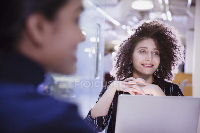 Smiling businesswoman at laptop listening in conference room meeting — Stock Photo