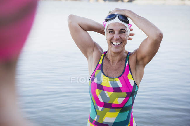 Женщина улыбающаяся пловчиха смотрит в камеру на берегу — стоковое фото