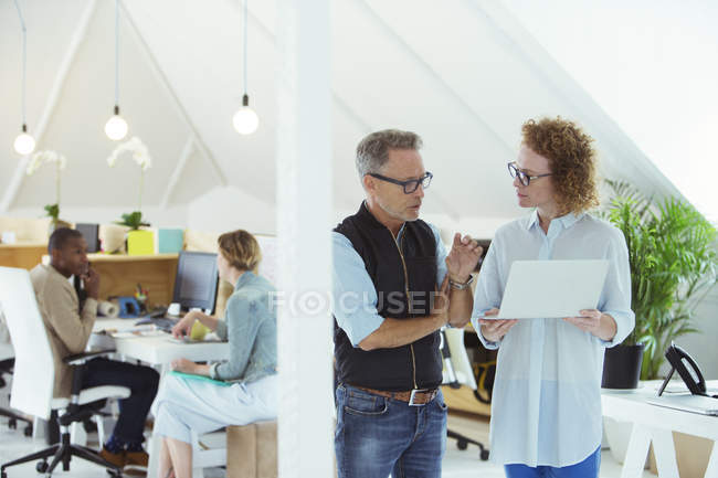 Two smiling office workers using laptop — Stock Photo