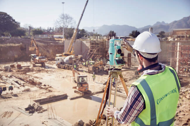 Construction worker surveyor using theodolite at sunny construction site — Stock Photo