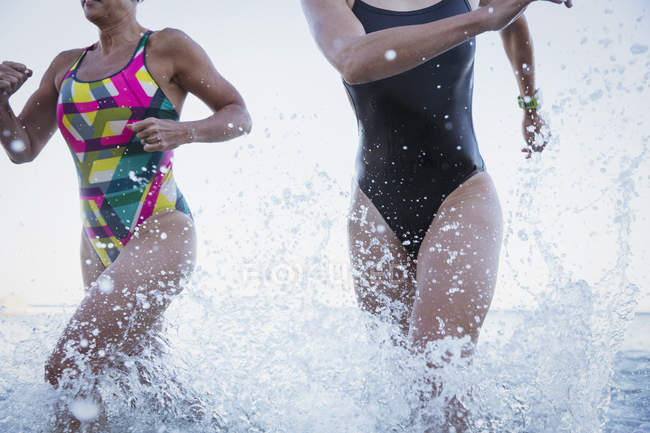 Mulheres nadadoras ativas correndo no oceano ao ar livre — Fotografia de Stock
