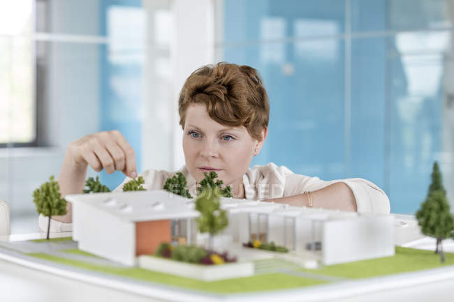 Female architect arranging building model in office — Stock Photo
