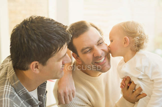 Affectionate baby son kissing male gay parents — Stock Photo