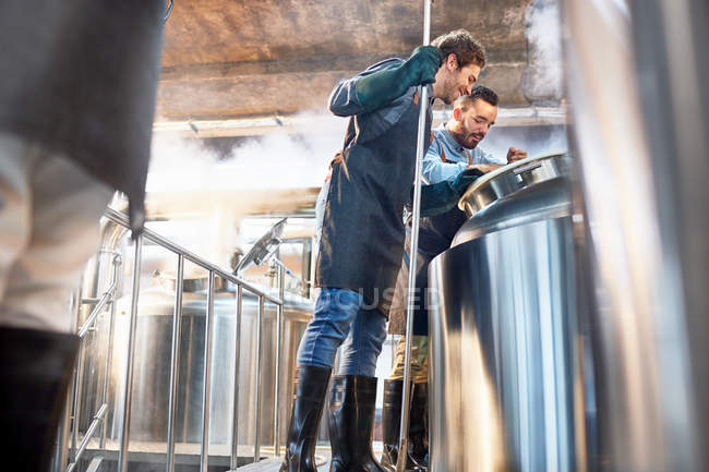 Мужские пивовары проверяют чан в пивоварне — стоковое фото