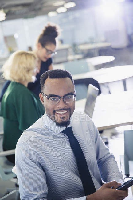 Portrait smiling businessman texting with cell phone in office — Stock Photo