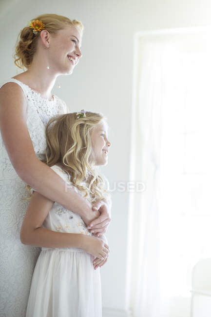 Braut umarmt Brautjungfer und schaut aus dem Fenster — Stockfoto
