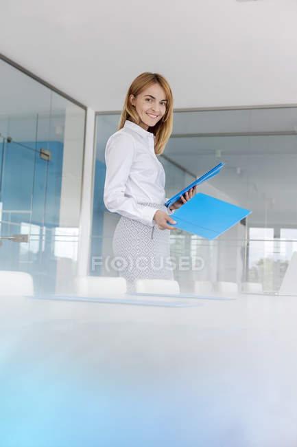 Портрет улыбающейся бизнесвумен кладет папки на стол конференции — стоковое фото