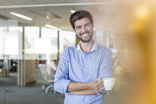 Retrato confiante empresário beber café no escritório — Fotografia de Stock