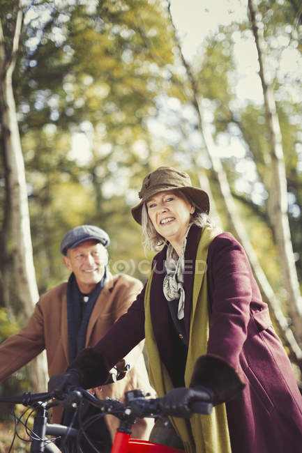 Portrait smiling senior couple bike riding in autumn park — Stock Photo