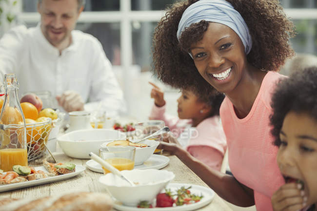 Portrait smiling mother eating breakfast with young family at table — Stock Photo