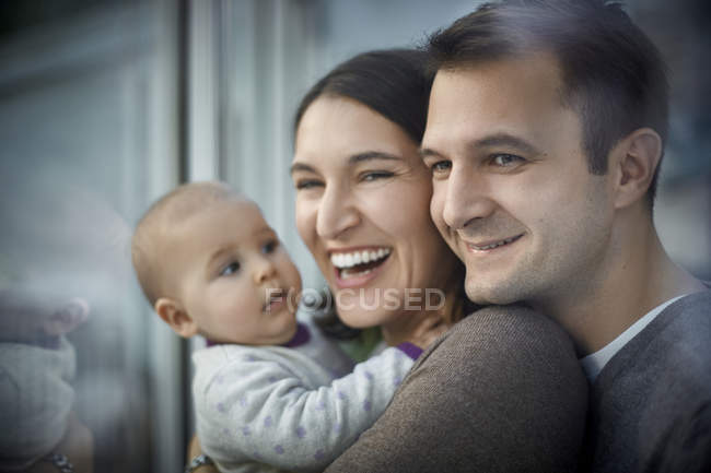 Smiling happy parents holding baby daughter — Stock Photo