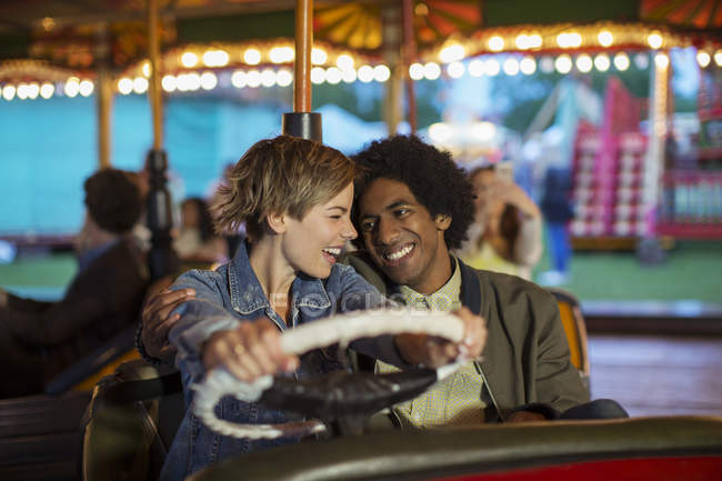 Jovem casal no pára-choques passeio de carro no parque de diversões — Fotografia de Stock