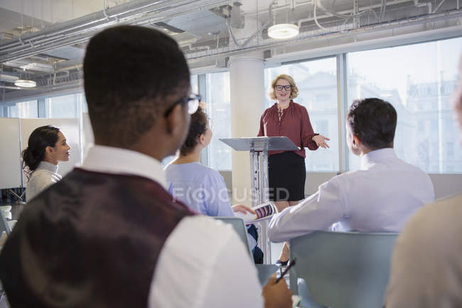 Businesswoman at podium leading conference presentation — Stock Photo