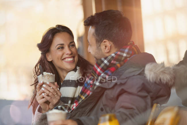 Улыбающаяся молодая пара пьет молочные коктейли в кафе на тротуаре — стоковое фото