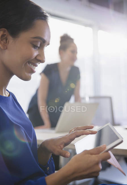 Femme d'affaires souriante utilisant une tablette numérique dans une réunion de salle de conférence — Photo de stock