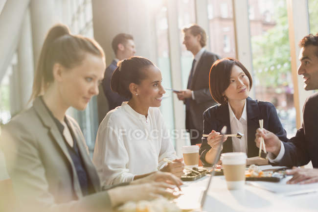 Business people eating sushi lunch with chopsticks in conference room meeting — Stock Photo