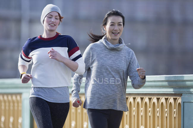Des coureuses souriantes courent le long de la rampe — Photo de stock
