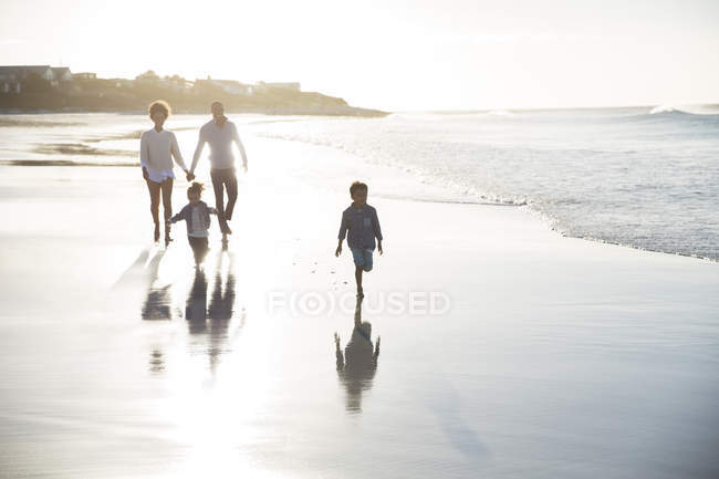 Familie spaziert bei Sonnenuntergang am Strand — Stockfoto