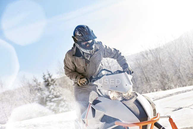 Hombre montando moto de nieve en soleado campo de nieve - foto de stock