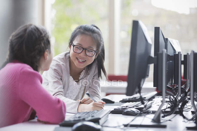 Smiling girl students researching at computer in laboratory classroom — Stock Photo