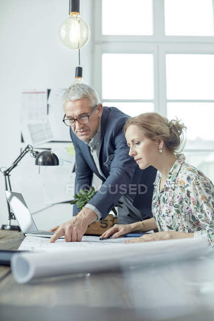 Architects discussing, reviewing blueprints in office — Stock Photo