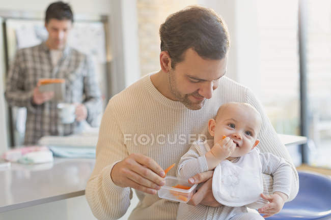 Pai alimentando cenouras para o bebê filho — Fotografia de Stock