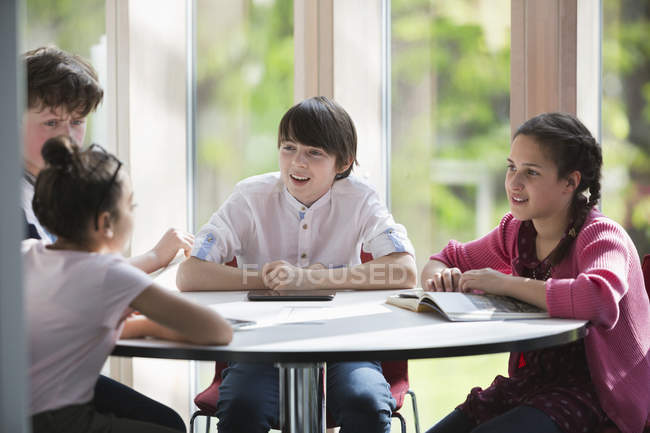 Students talking at table in library — Stock Photo