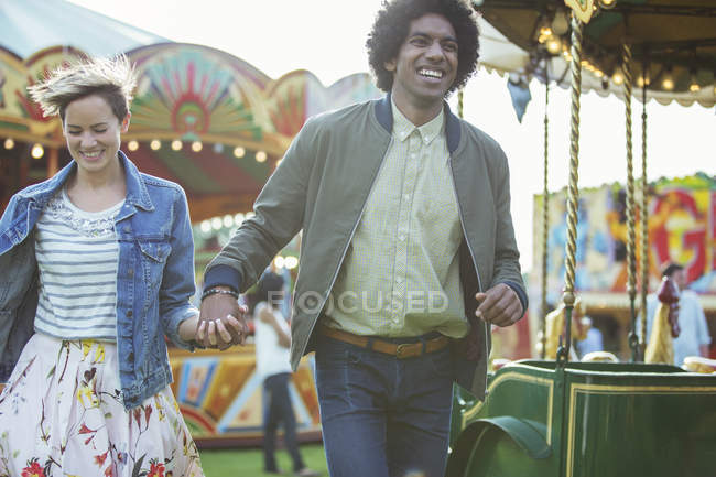 Jovem casal multirracial se divertindo no parque de diversões — Fotografia de Stock