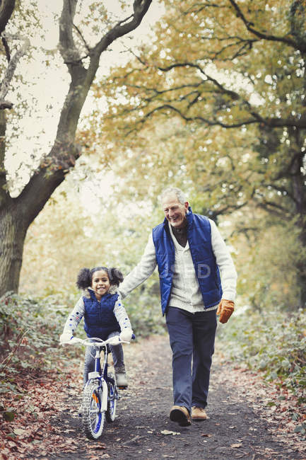 Grandfather and granddaughter bike riding on path in autumn park — Stock Photo