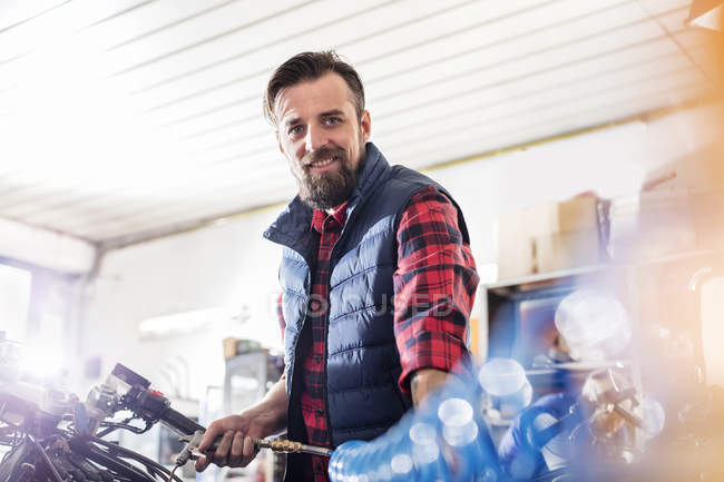 Ritratto fiducioso meccanico motociclista di sesso maschile che lavora in officina — Foto stock