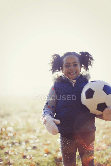Портрет усміхненої дівчини з футбольним м'ячем у сонячному осінньому парку — стокове фото
