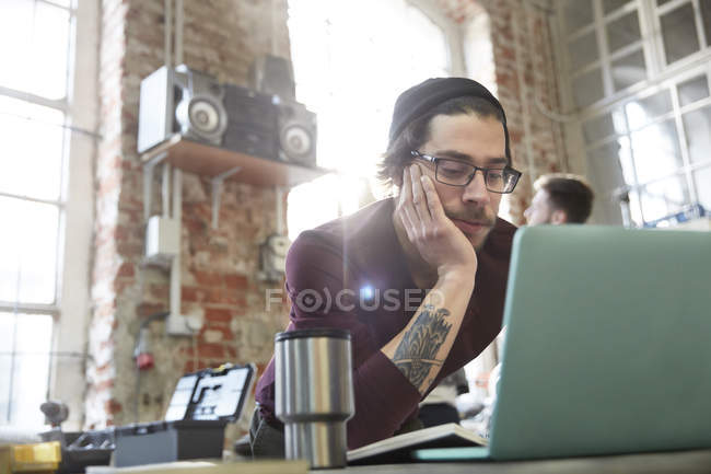 Young male designer using laptop in workshop — Stock Photo