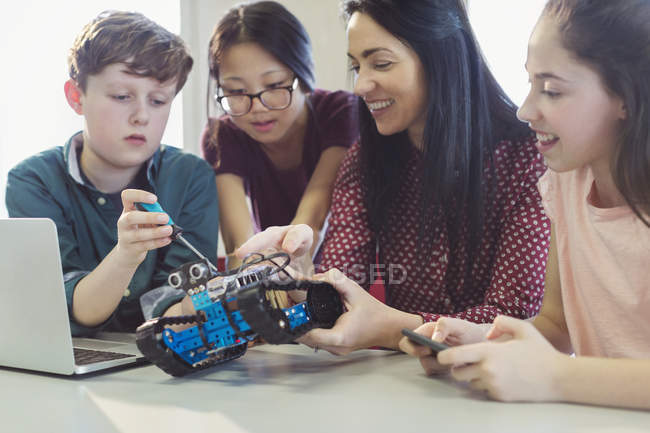 Female teacher and students programming and assembling robotics in classroom — Stock Photo