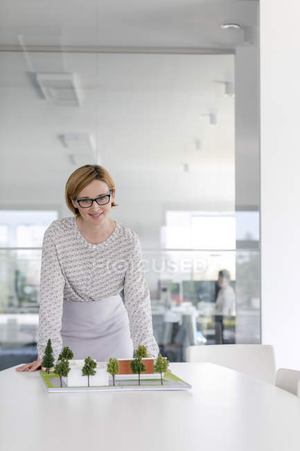 Retrato confiante arquiteto feminino com modelo na sala de conferências — Fotografia de Stock