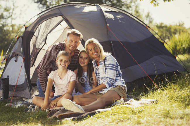 Portrait smiling family relaxing outside sunny campsite tent — Stock Photo
