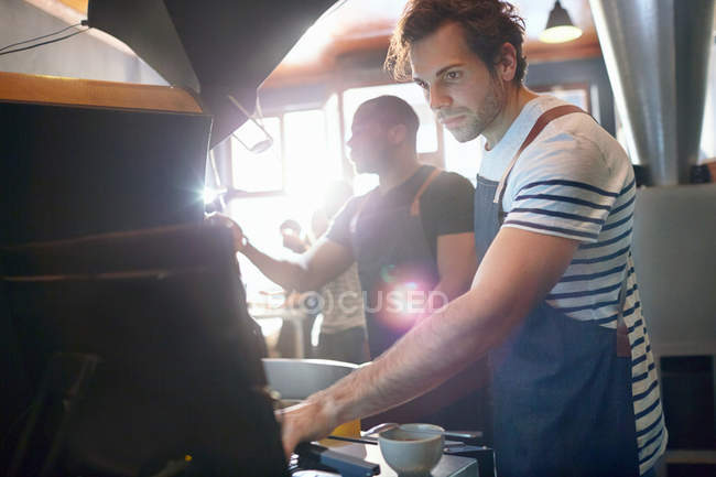 Asadores de café masculinos enfocados trabajando, usando computadora - foto de stock