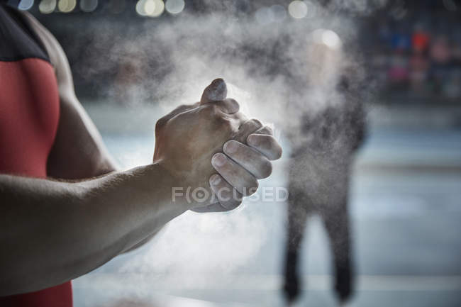 Levantamiento de pesas masculino de cerca aplicando polvo de tiza en las manos - foto de stock