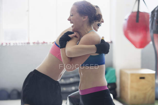 Boxer femminili sorridenti che si abbracciano in palestra — Foto stock