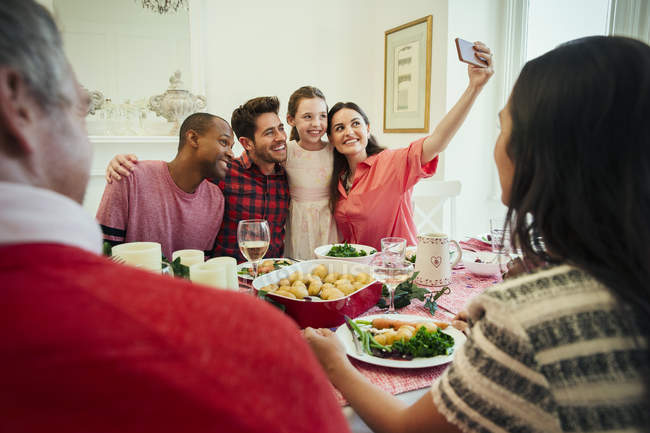 Famiglia multietnica con fotocamera cellulare scattare selfie a tavola a Natale — Foto stock