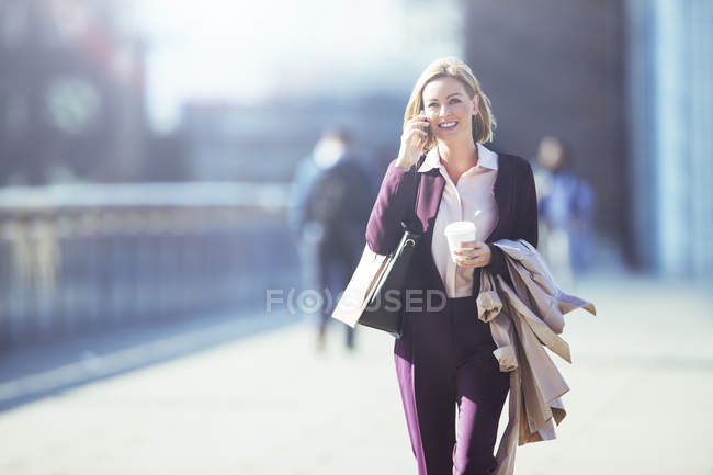 Businesswoman talking on cell phone on city sidewalk — Stock Photo