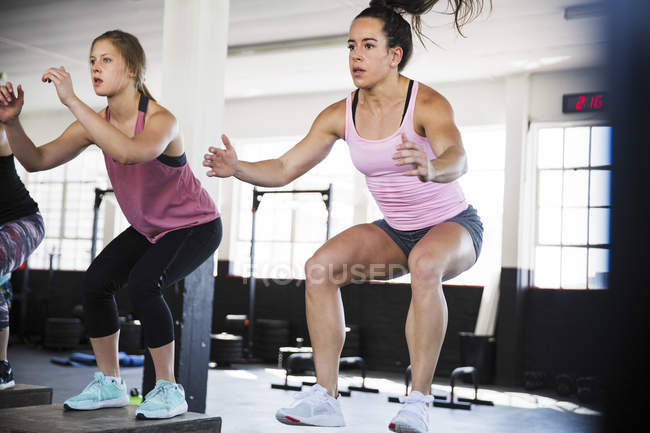 Jeunes femmes déterminées à faire des squats de saut en classe d'exercice — Photo de stock