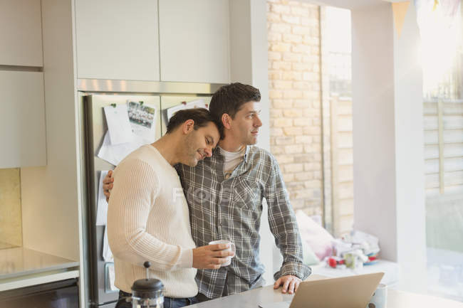 Affectionate male gay couple with coffee in kitchen — Stock Photo